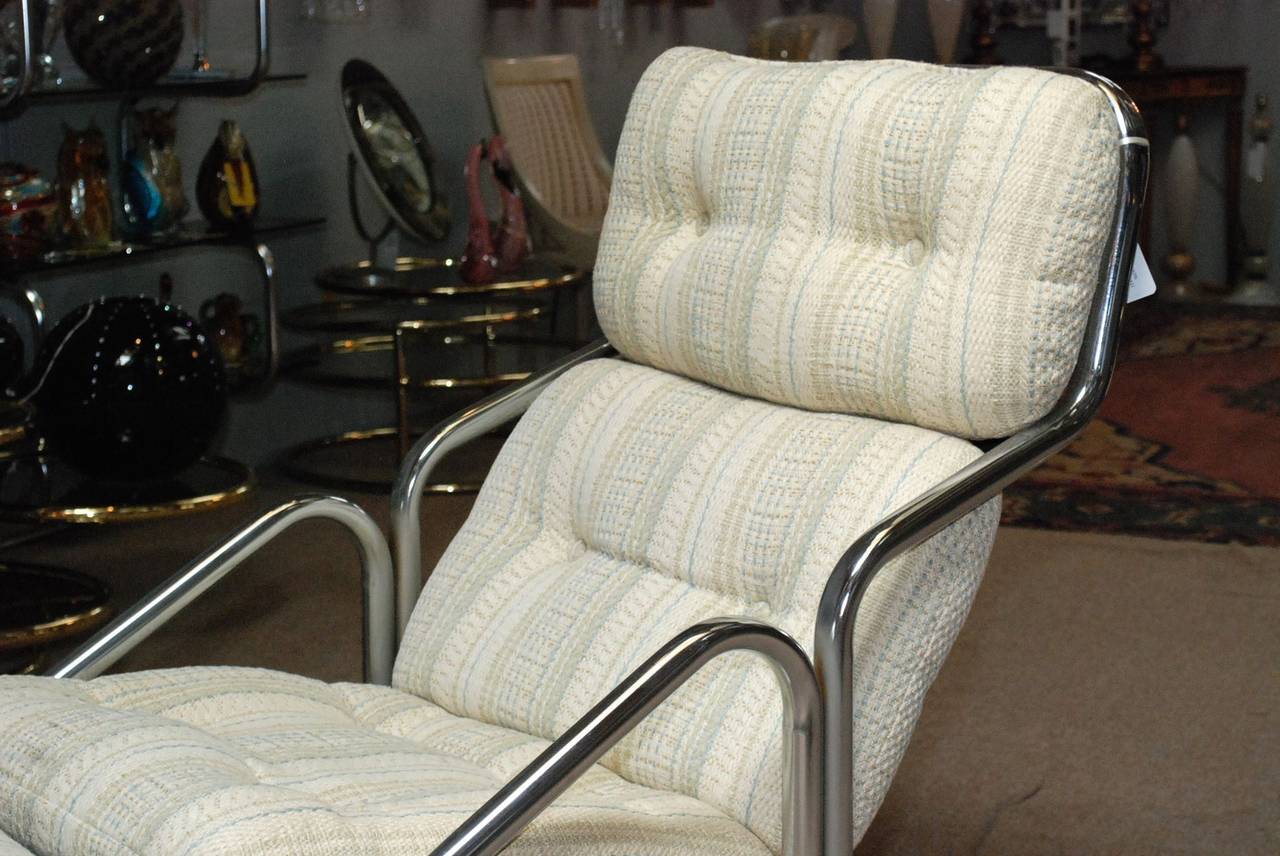 A midcentury lounge chair with attached ottoman by Jerry Johnson. Frame is in chrome and the upholstery is in lightly striped nubby wide patterned chenille.