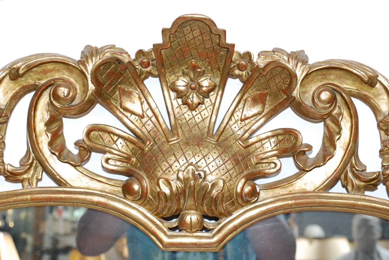 A pair of 20th century French Rococo style gold leaf mirrors with shaped scrolled. Hand-carved wood.