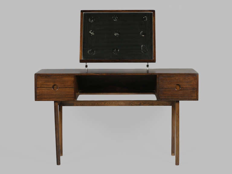 Über minimal and sleek 1960's rosewood vanity by Aksel Kjaersgaard.  Features streamline design, 3 drawers with circular pulls and adjustable mirror with stainless hardware.

Location: ABC Home, 888 Broadway 2nd Floor, New York.