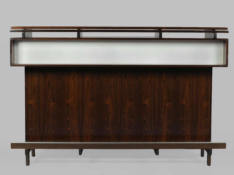 Generously-proportioned Rosewood Bar fully equipped with bottle holders, black laminate surface, utensil drawers with leather pulls, storage cabinets, and a stainless steel bucket for ice or garnishes.