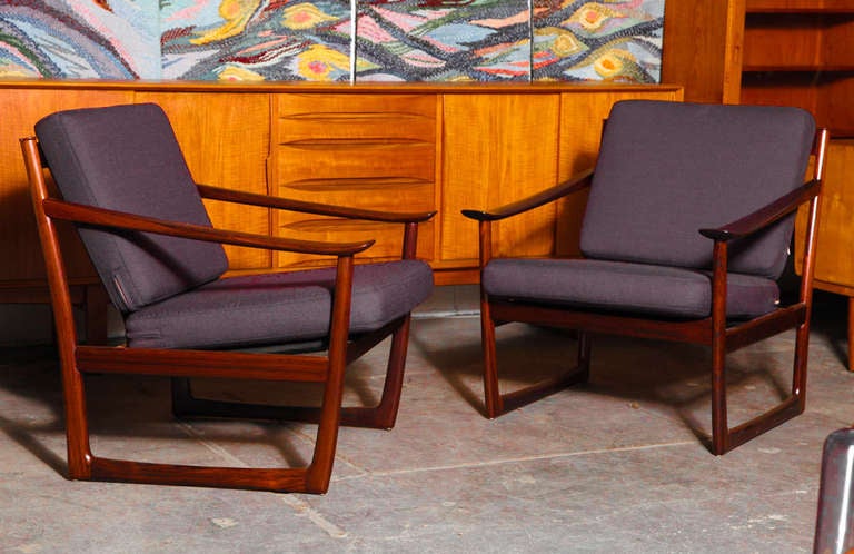 Elegant pair of rosewood arm chairs designed by Hvidt and Molgaard in the 1960's. Features a rosewood frame, slatted back, sleigh legs, and newly upholstered in an opulent aubergine fabric.