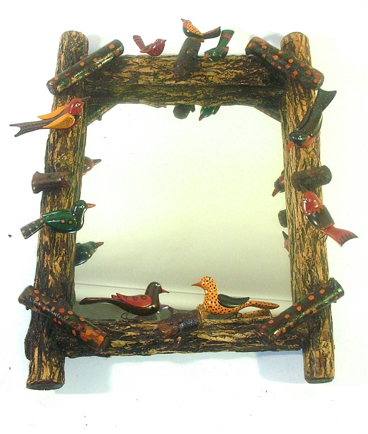 A whimsical example of an American Folk Art mirror and frame. This mirror would be at home in any design environment, the hand-carved variety of birds are cheerfully finished with a strong paint color palette. The spindly wire form bird legs add to