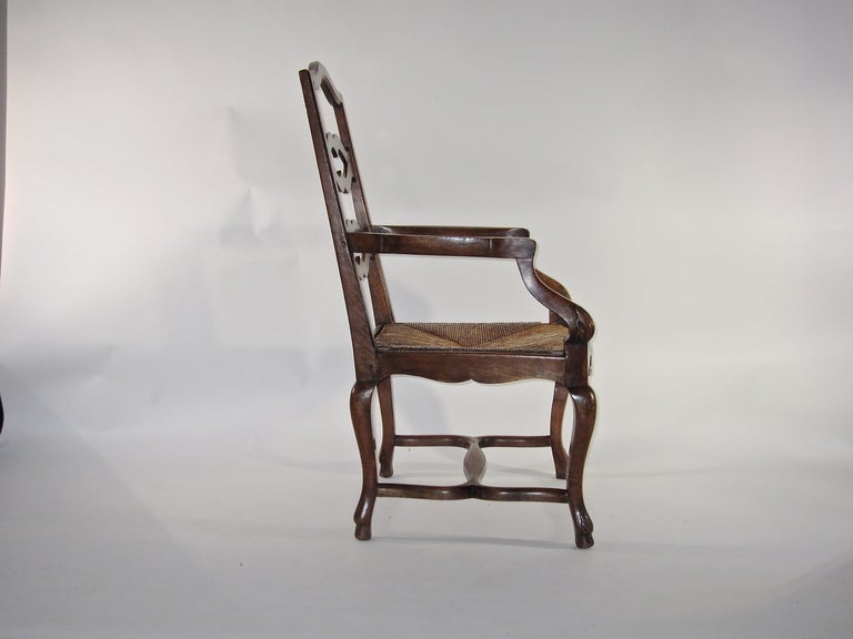 A well proportioned large armchair with rush seat. Comfort and condition are offered in the French made chair, with carved details on legs and back.