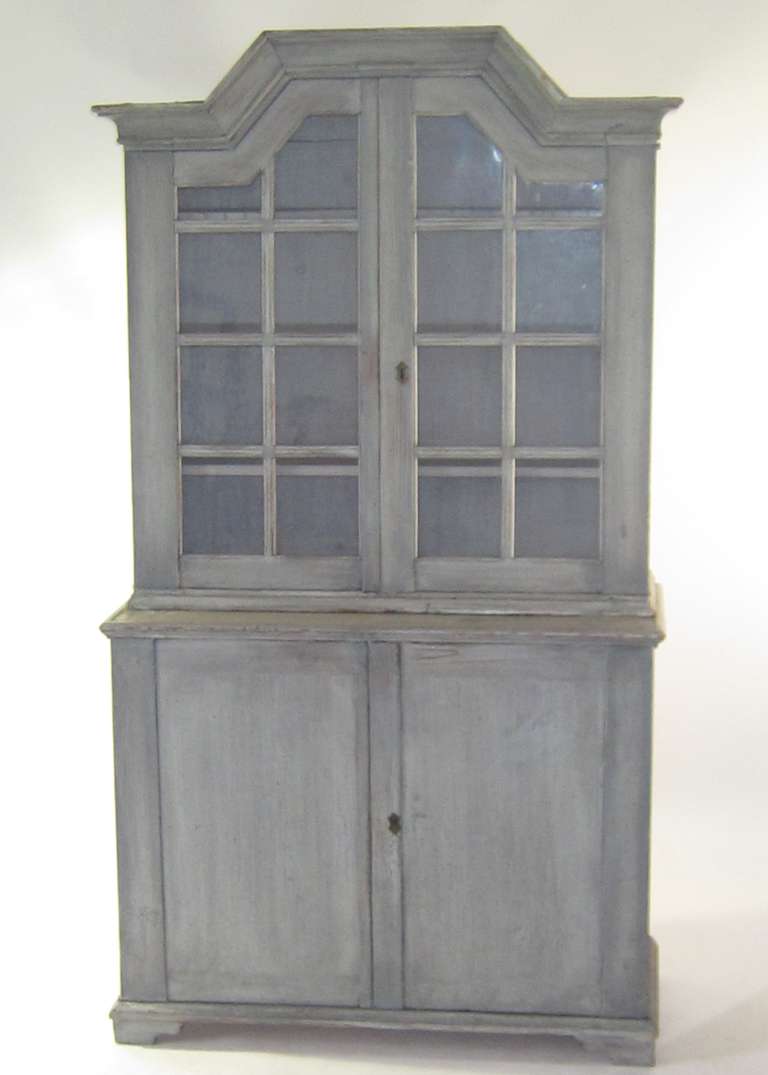 A handsome stepped back four-door cupboard with original locks and keys, glazed upper doors and shelving.