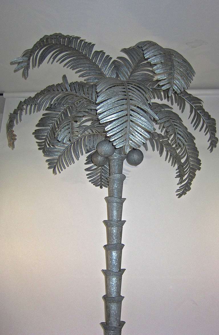 This Coconut Palm tree made of  formed galvanized tin is life like, stunning and has three coconuts to boot. Depending how you position the fronds it stands about eight feet plus tall. The tree has details on the base. Certainly an eye catcher.