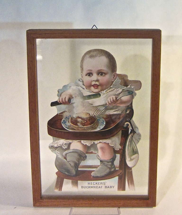 A litho on paperboard  advertising store tag framed between glass to offer a floating image. Heckers was prolific in their advertising campaigns. This fine little baby certainly looks like she not only enjoys the buckwheat cakes but has benefitted
