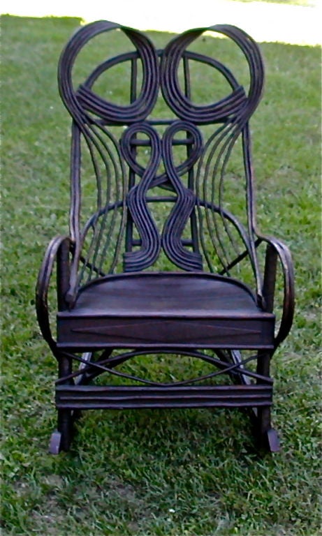 A fine example of American handcrafted rockers. The chair back design flows with circulating movement. The struts and upright supports are carved. This chair offers a generous and most comfortable seat.