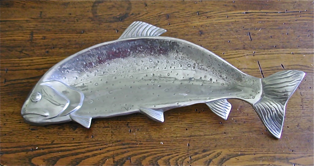 This highly stylized serving dish designed and signed by Bruce Fox from New Albany, Indiana is one of his design creations inspired by nature. Made from a pure aluminum, safe for food service as stated in the company's literature. This Rainbow Trout