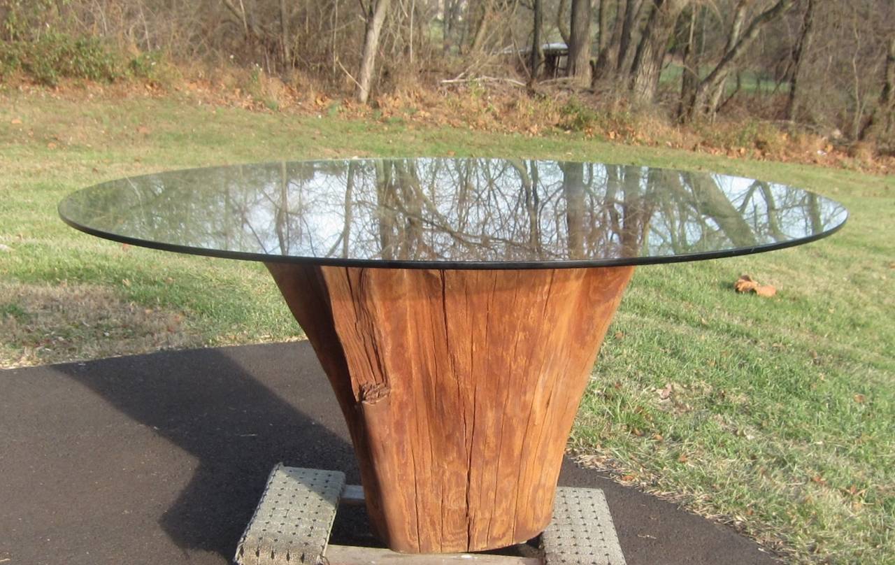 This fine specimen of a southern cypress tree trunk is fitted with a 60 inch glass tabletop which will accommodate eight people . The visually strong shape is structurally sound and can be placed outdoors for use on porch, patio or garden.