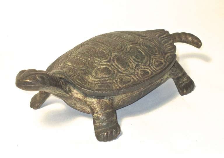 This heavy brass hinged opening box of a smiling turtle  is well detailed and the surface is as found with old patination over the brass body. An amusing tabletop storage box.