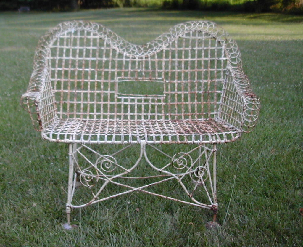 An early heavy gauged iron and formed wire embellished garden bench with heavy duty floor guards.