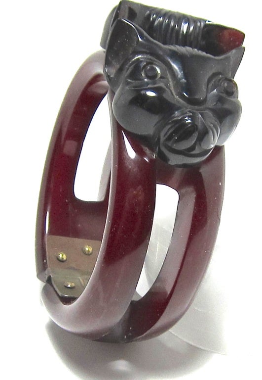 A rare and unusual Bakelite clamper bangle featuring a pair of cat heads. The bracelet is in dark wine red color, the cat heads are black.