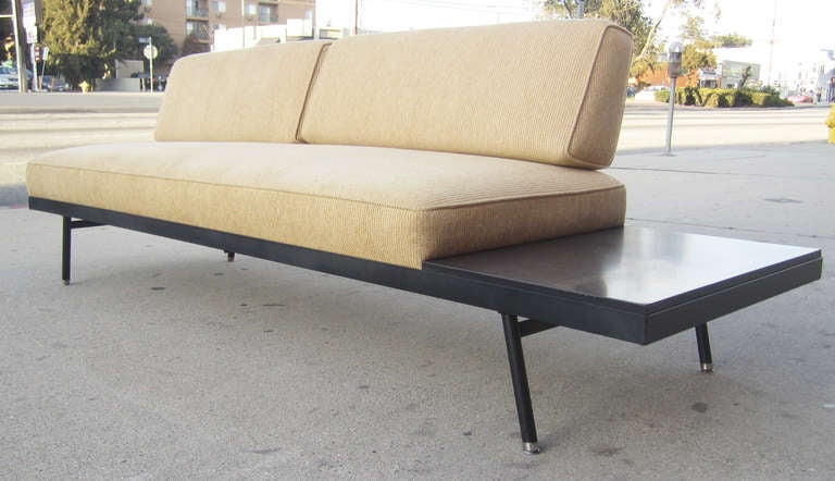 This mid-century sofa by Vista of California features features three comfortable seats with an attached black Formica side table. The angled back cushions are held in place by a minimal wrought iron frame. The sofa is supported by spayed metal legs