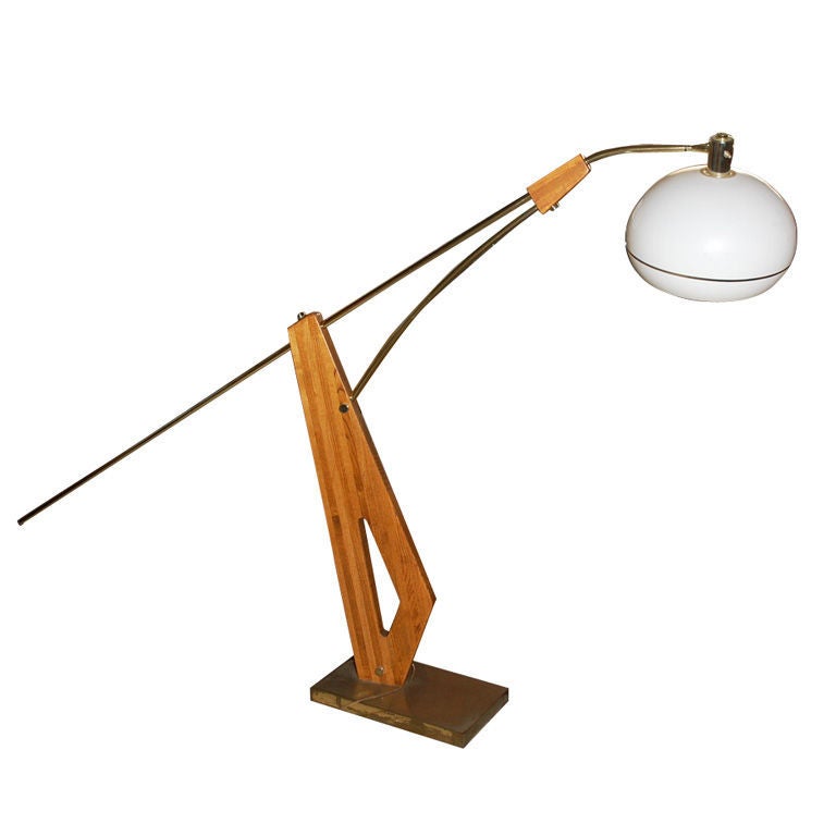 A large sculptural California adjustable arc lamp with a white acrylic shade and brass tubing set on a base of light colored oak and brass.