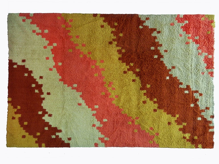 This rug features an alternation of 4 different color stripes:mustard, coral, wine and beige. The pile is dense and thick.