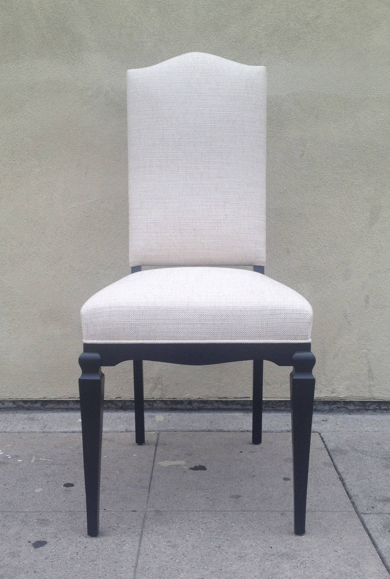 This set of elegant dining chairs features a clean ebonized wood frame and white-beige tweed upholstery.