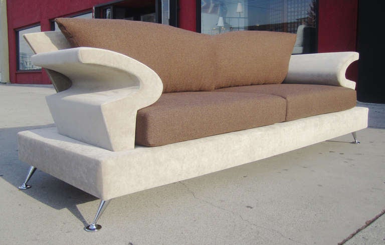 This playful, Memphis-style sofa features sculptural arms and a flared back atop a rectangular base. The Italian-made sofa by B&B Italia rests on flared chrome legs with disc feet. The two-tone upholstery adds to the drama of the piece.