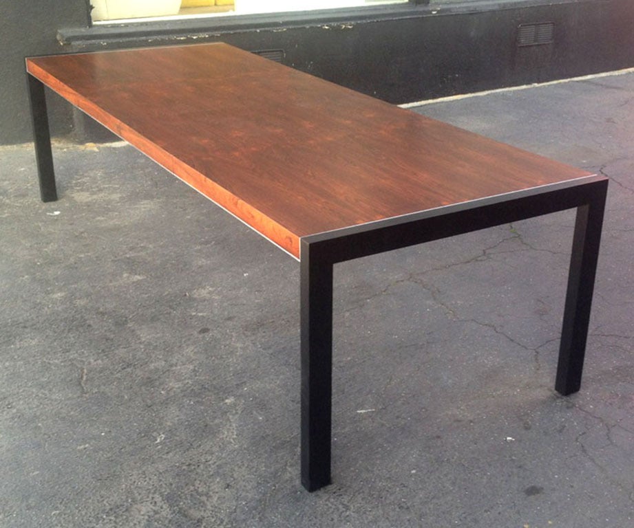 The table top is made of rosewood and the legs made of black stained wood which continue along the outer edge of the top. A thin line of chrome frames the table top creating a beautiful horizon line. The two leaves measuring 19