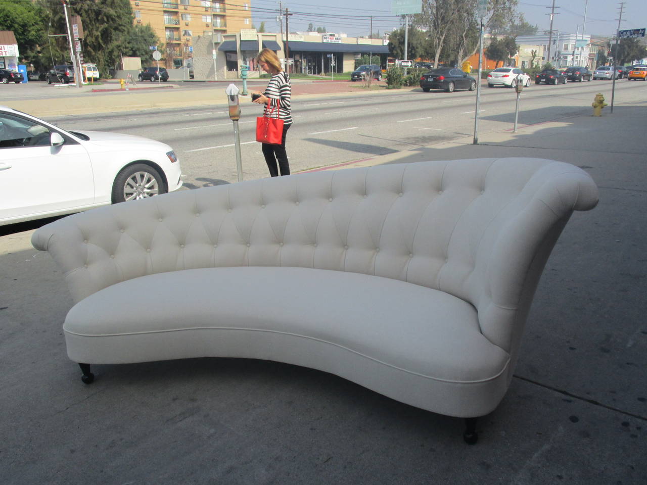 A glamorous Hollywood Regency sofa with a unique asymmetrical frame. The elegant white upholstery and black feet on this piece downplays the ornate shape and tufting of the backrest, increasing its versatility.
Measures: The height of the lower arm