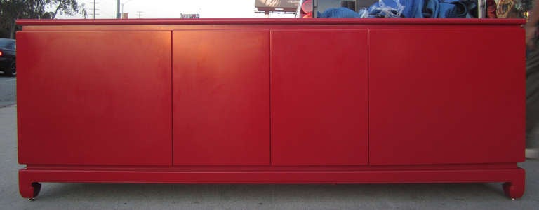 This handsome credenza / cabinet features a cadmium red lacquer finish. The two central doors open to reveal pull-out shelving surmounted by a drawer; behind each of the flanking doors is a single shelf and drawer.
The credenza rests on an