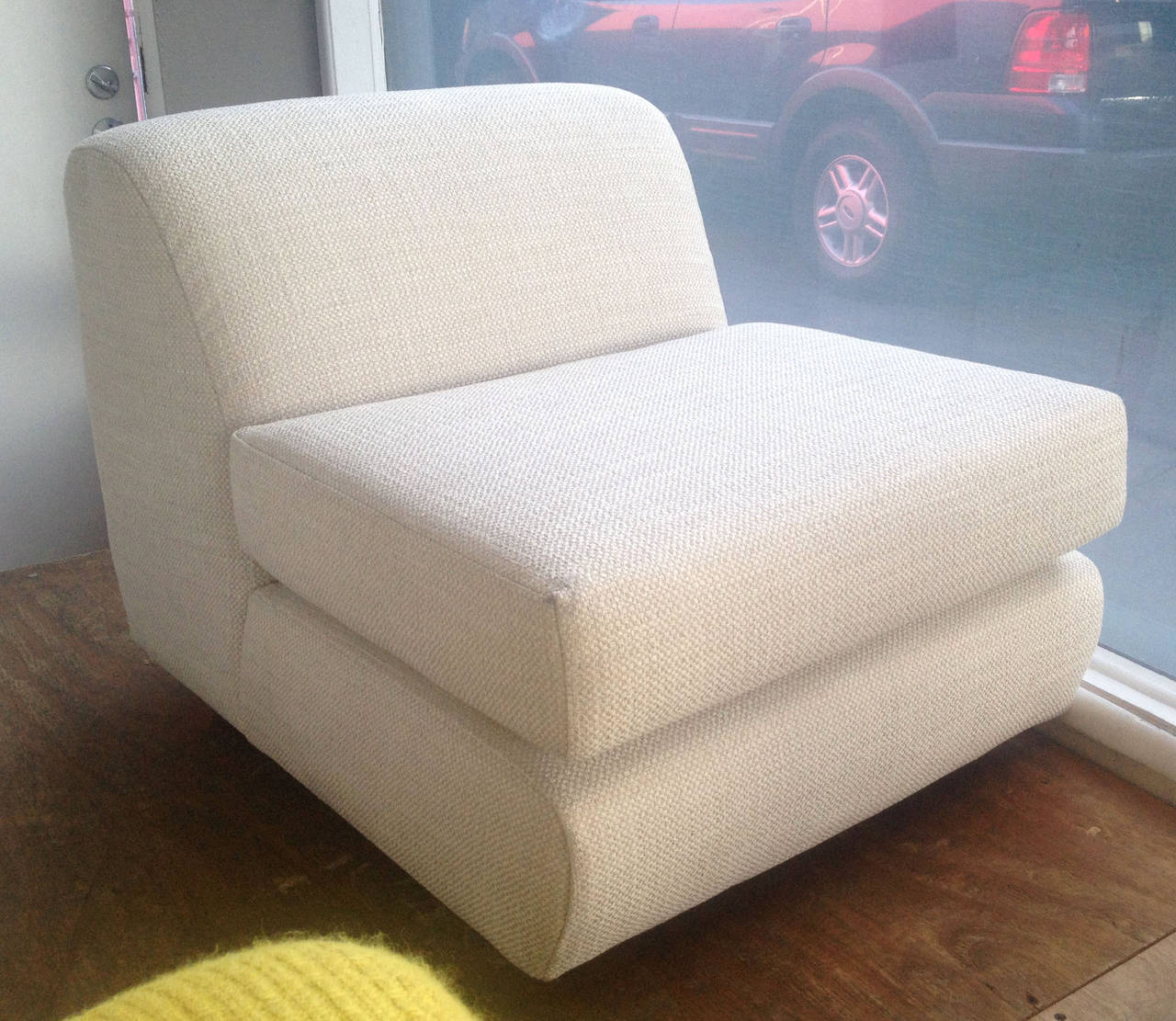 A pair of slipper chairs with a nice off-white tweed upholstery. Each rectangular chair is supported by four small wooden peg legs.