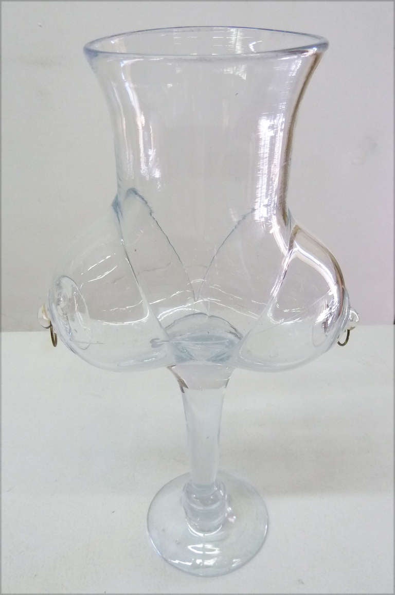 This unconventional figural glass vase / goblet features a woman's naked torso with two pronounced brass piercings. The work is
illegibly signed at the base.
