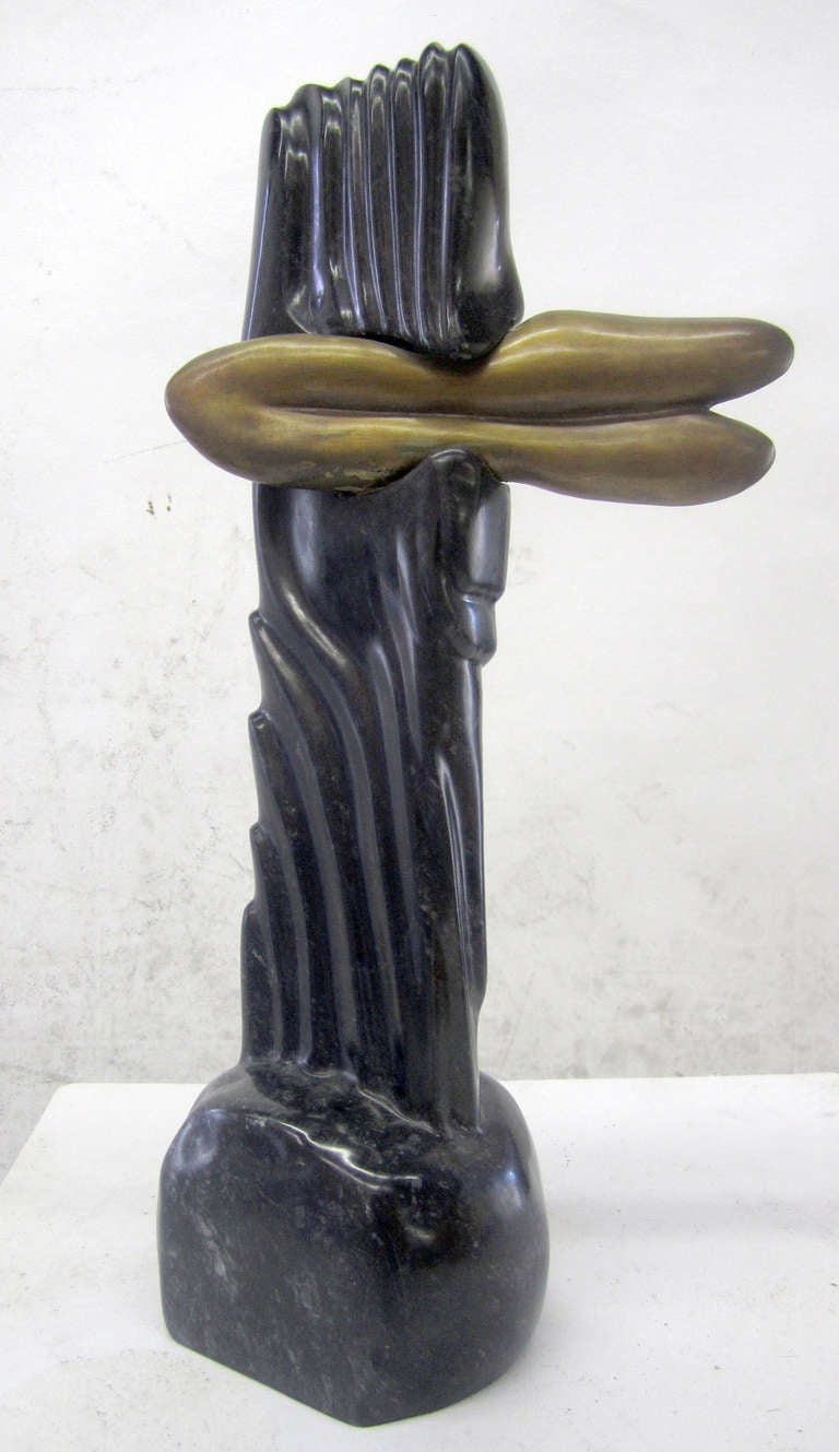 This odd, amorphic sculpture features a ribbed, black marble body which seems to be grasping the brass part, creating a surreal, almost human-like effect. The piece is not signed or dated.