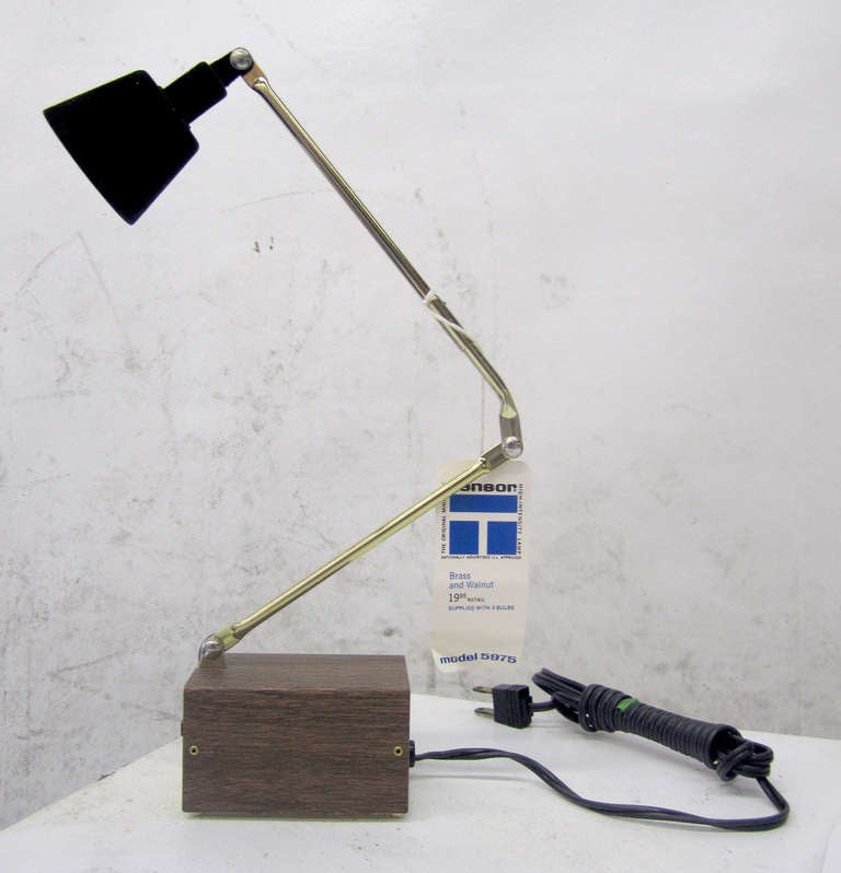 This tres petite desk lamp featuring a walnut & brass body still retains its original Tensor tag. It has never been used and was still in its box. This particular desk lamp was one of the first to use a high-intensity bulb; the shade is covered in a