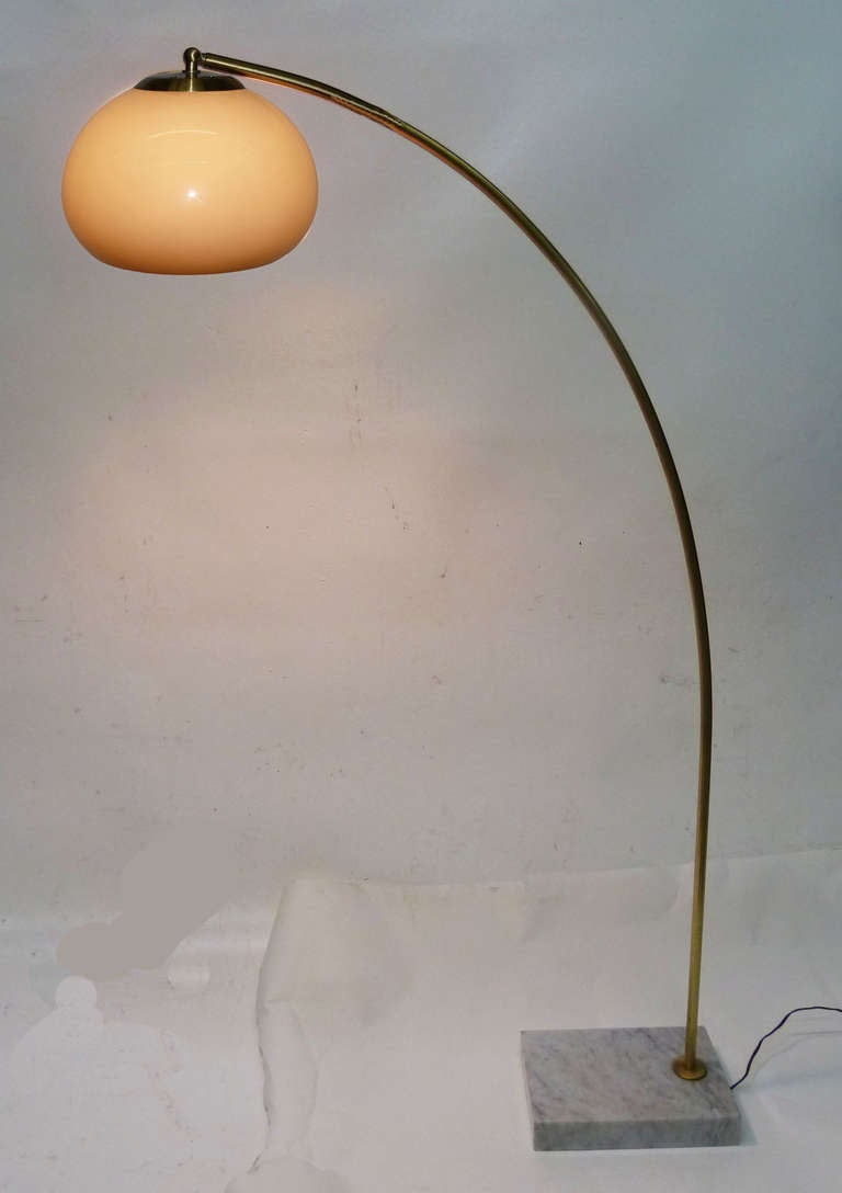 This mid-century modern arcing floor lamp features a domed plastic shade which appears smoked when off but turns a pale orange when lit. The arm of the lamp is rendered in brass while the base is marble.
The base is 7