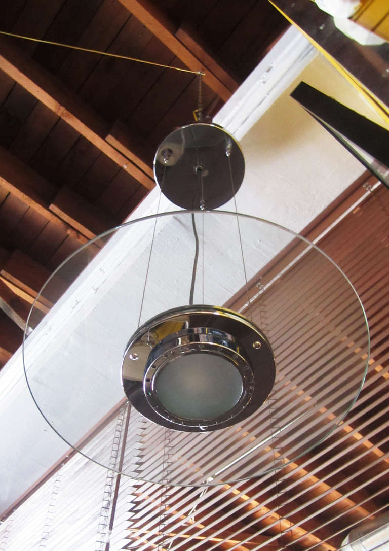 This iconic 1980s suspension lamps by George Kovacs feature a round light embedded in a thick, glass disc. Each of the stylish pendants are suspended from three tension wires which connect to a chrome canopy.