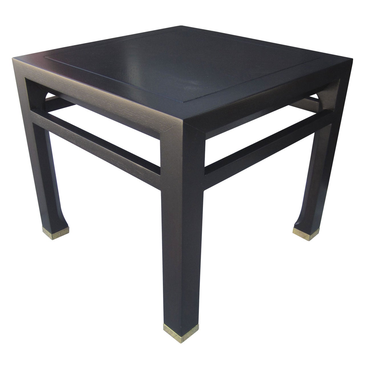 Pair of stunning side or end tables with ebonized finish and brass sabots by Michael Taylor for Baker Furniture. Unusual styling with channelled detailing around the perimeter of the top and tapered legs that widen at the brass capped foot. The