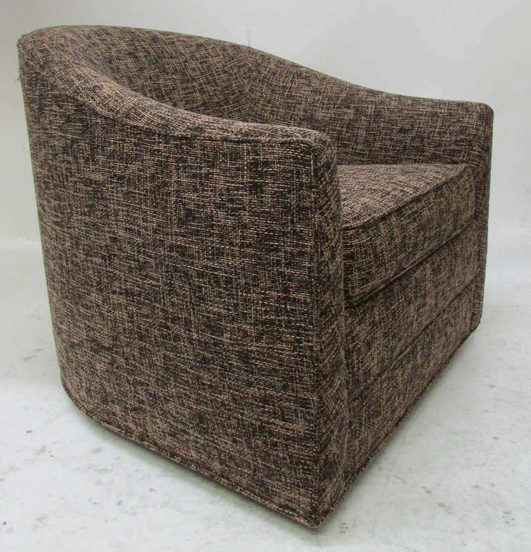 This compact barrel chair by Harvey Probber features a swiveling base and a removable seat cushion. The piece has been newly reupholstered in woven brown and beige fabric.