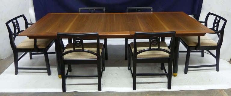 This handsome mid-century modern dining room set by Michael Taylor for Baker features the designer's signature interlocking carved rings on the back of the chairs. 
The set includes four side chairs, two captain's chairs and 3 leaves measuring 12