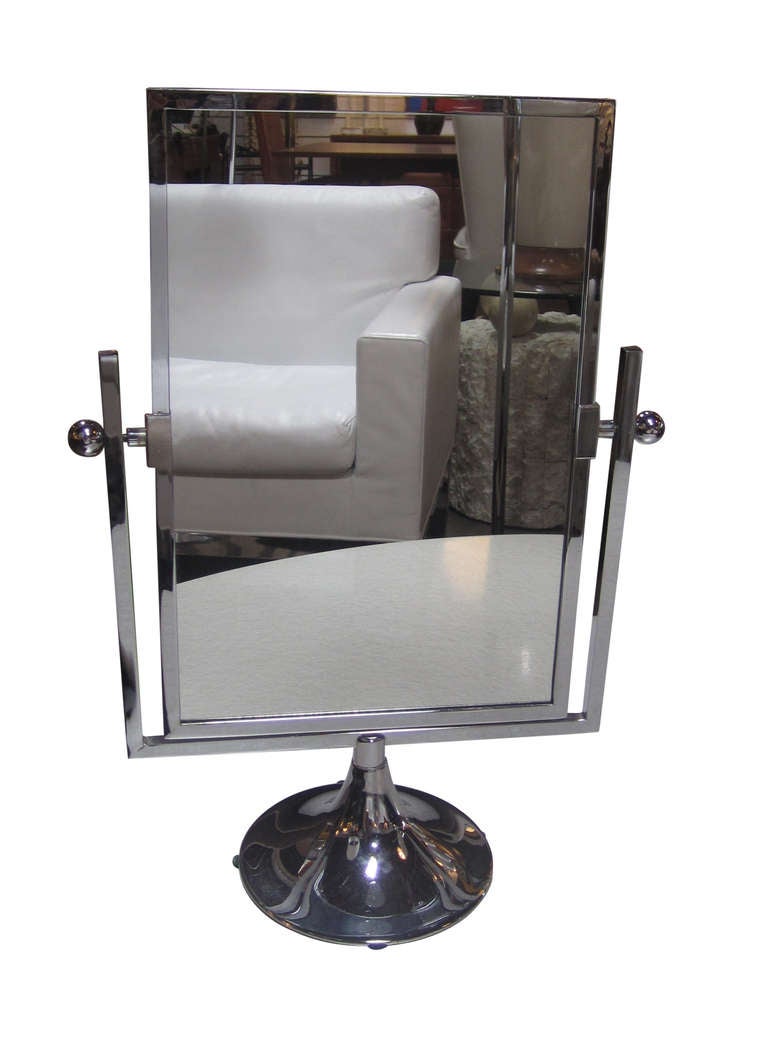 This unique vanity mirror by Charles Hollis Jones rotates 360 degrees to reveal a mirror on both sides. Its frame and flared support are all in chrome.