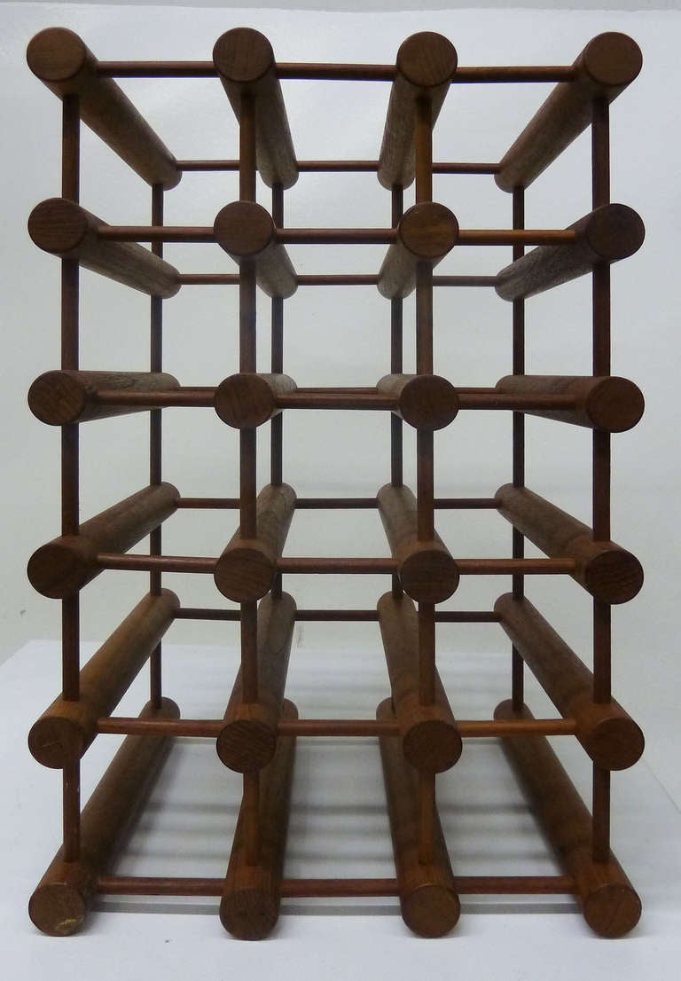 This Danish Modern wine rack by designed by Richard Nissen features multiple teak dowels arranged in an artful and architectural way to accommodate up to fifteen wine bottles.
One of the rods bears the following insignia, 