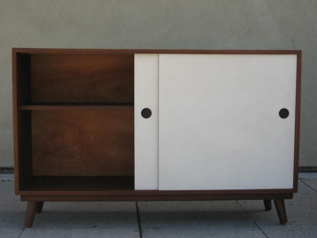 Very simple walnut credenza with 2 white lacquered sliding doors.<br />
The right door opens on a drawer and a shelf while the left one on only a shelf. It sits on 4 tapered legs.