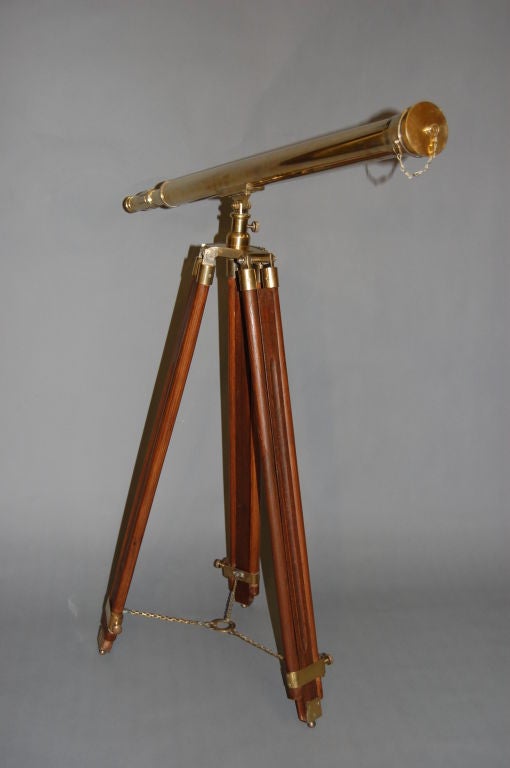 Turn of the Century brass telescope with adjustable tripod base.  This decorative telescope has a stargazing or nautical design. The length of the scope is 39” and the lens is 2 ½” in diameter. The tripod legs can adjust to a maximum of 63” height.
