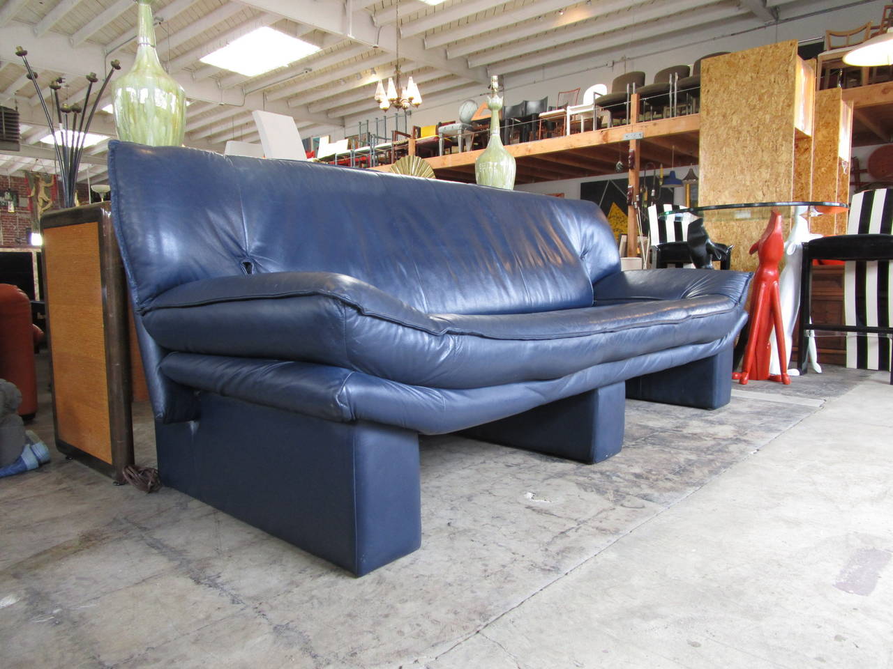 Blue leather sofa on three supports, entirely clad in leather. 
Strong lines and very comfortable.
The leather is soft and thick at the same time.