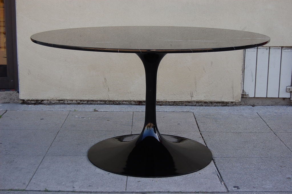 Classic Pedestal Tulip dining table  by Finnish American architect Eero Saarinen. This table was developed by Saarinen in the late 40's and later put into production in 1956. Top is a stunning polished slab of black marble in a round shape and has