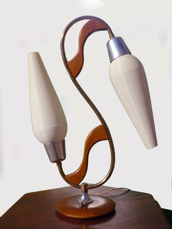 This whimsical table lamp utilizes brass, aluminum, and shaped wood in its construction.  The cone-like shades are made of coiled plastic. The switch is found on the base.
