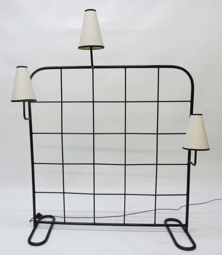 This rare room divider and luminaire by Jean Royère (1902-1981) was designed in France in 1949. It is fabricated from enameled wrought-iron woven to create a grid like pattern and embellished with three lights with parchment shades.
Literature: