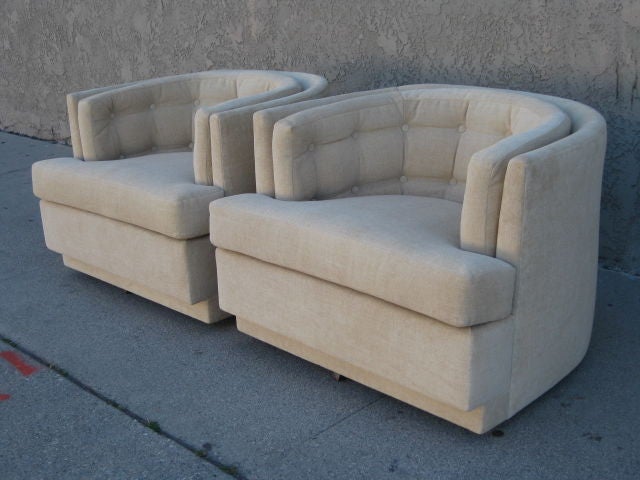 Pair of two barrel chairs from the 1960's. Both chairs have a swivel mechanism at the base. The seats have a light beige color upholstery with the backrests tufted. They sit low and wide. <br />
Very comfortable.
