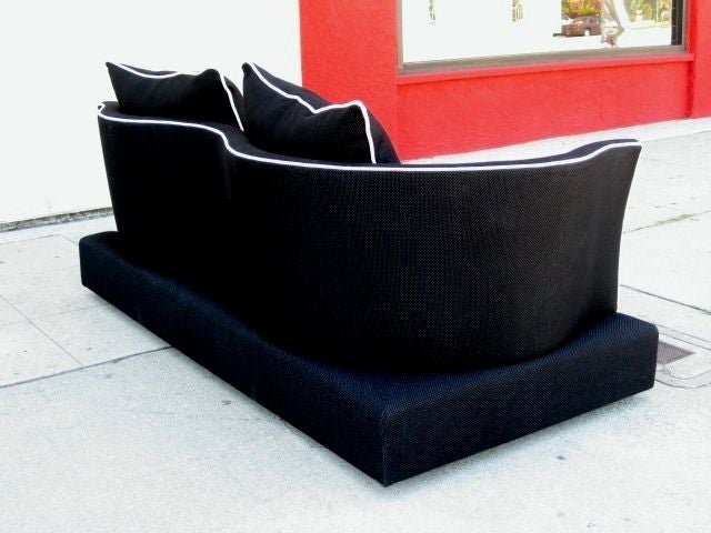 This loveseat is upholstered in a dense cotton blend black fabric.The edges of the backrest has been detailed with a off white piping that further pronounce the playful curves.Pillows also have been detailed with the same piping.<br />
The backrest