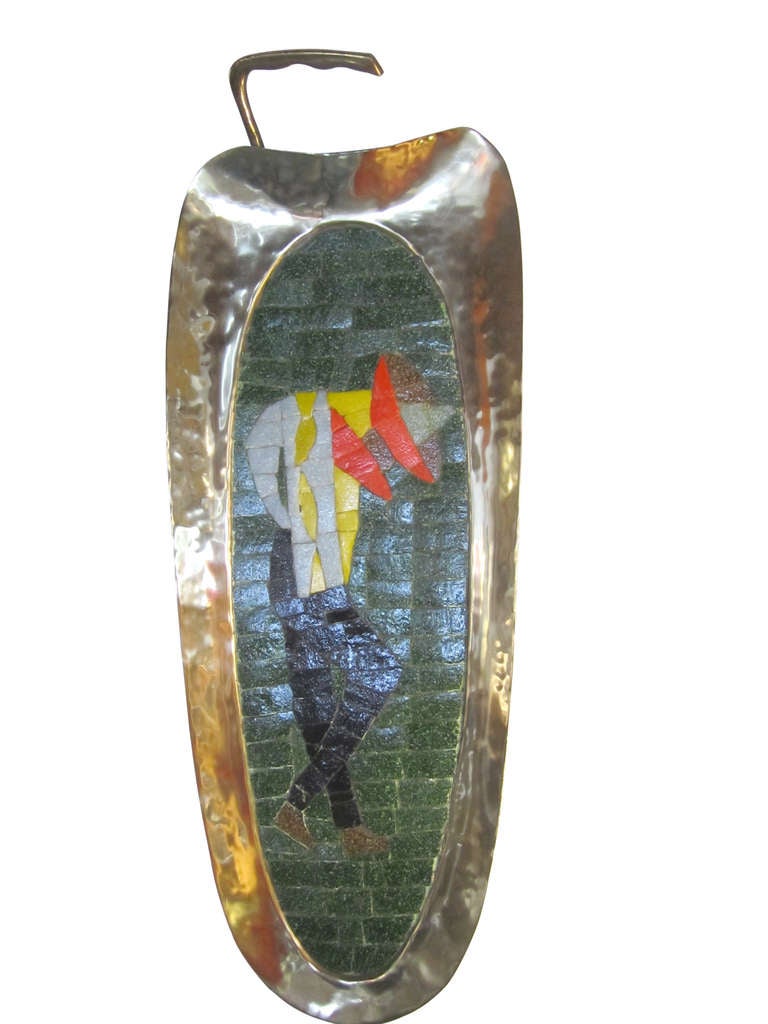 Handmade glass tile mosaic and brass tray by Salvador Teran. There is also a hanging ring on back side for wall display. The artistic mosaic component of this sculpture is mounted on to a heavy brass plate back. 
Made in Mexico, this piece depicts