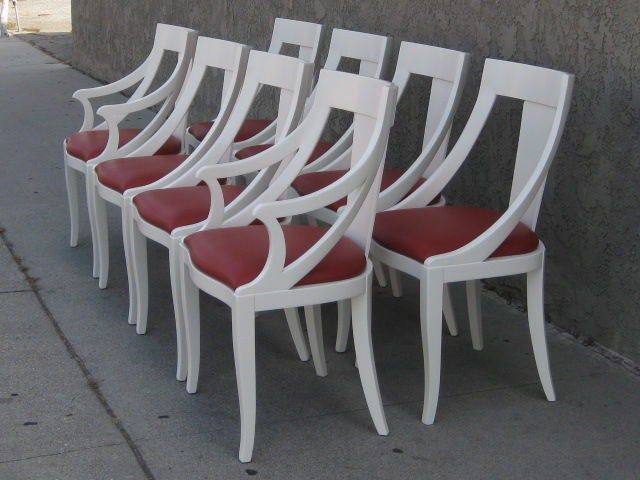 Elegant set of eight dining chairs lacquered white with a cool red leather seat cushion upholstery from the 1960s. The set includes six side chairs and two captain's chairs. The mid-century chairs have a slight curves and flares contributing to the