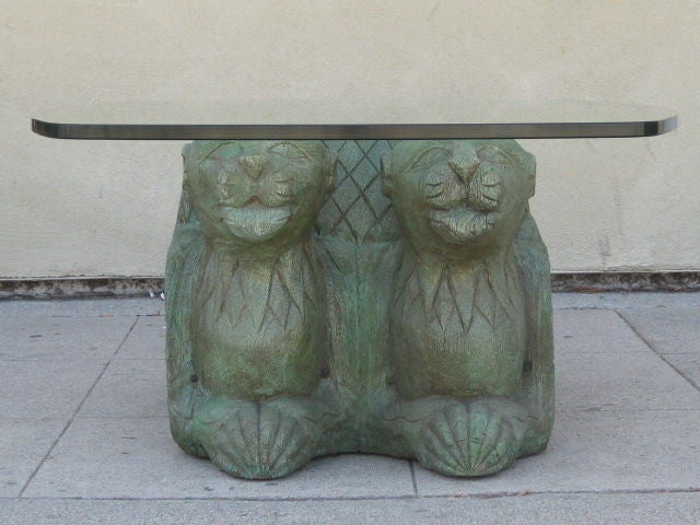 Unique glass top coffee table with a wood base, carved and shaped into four huddled panthers from the 1960s. The base figures have been colored in a greenish hue and hold up a 1” thick glass top.<br />
This very decorative table is a statement