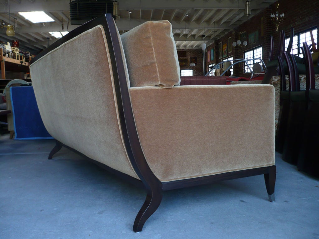 The sofa is upholstered in a warm beige mohair velvet and framed in dark rosewood. The front leg caps are finished with nickel plated end caps.