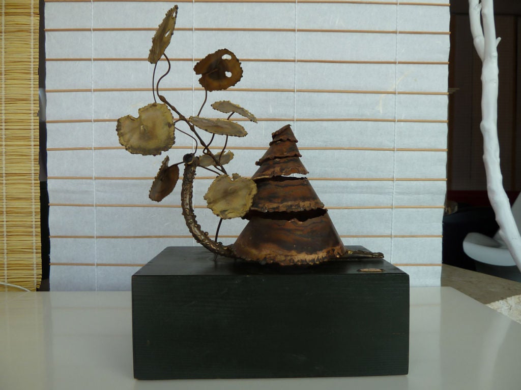 A whimsical, brass sculpture by Curtis Jere on a wooden base.