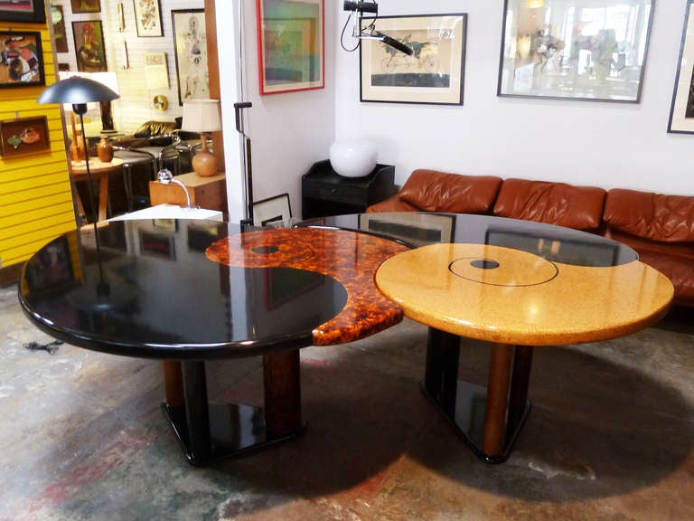 These high design, Memphis-style tables are individually supported by three cylindrical columns which terminate in a triangular base. The tables were designed to work in tandem, nesting comfortably together to form a large dining table or desk. The