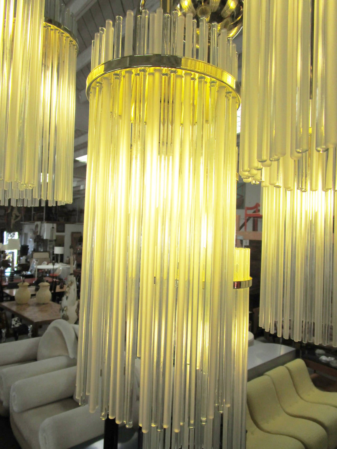 This glamorous chandelier is made up of ten brass arms which arc gracefully into cylindrical fixtures composed of individual rods of hand blown glass. The impressive artistry in glass as well as the impact of chandelier's grand scale makes this an